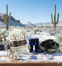 Hand and facial cream against a snowy desert backdrop on a wooden plank  next to a bag of 'clean coal"- which is soap for those who have been naughty