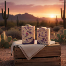 Two soap bars on a wooden crate with a desert sunset background