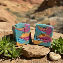 Two colorful soap bars on a rock with desert landscape in the background