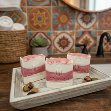 Three bars of soap on a wooden tray with a decorative tiled wall in the background