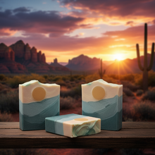 Three soap bars with a desert sunset landscape in the background