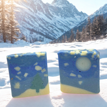 Two soap bars with a mountainous landscape in the background