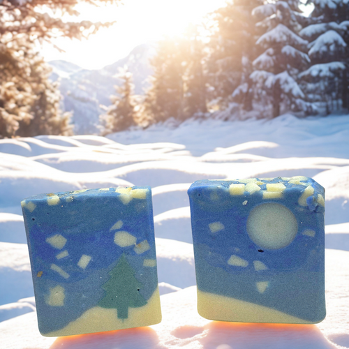 Two colorful soap bars in the snow with a mountain and trees in the background